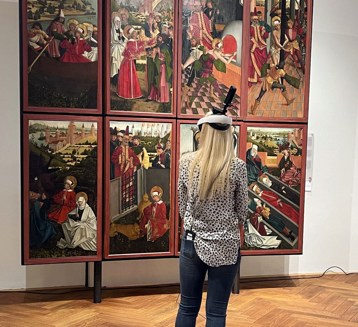 Der Guide. eine junge Frau, mit VR-Headset im Museum steht vor einem altertümlichen Tafelbild